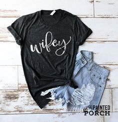 "Find this product and many more on our website www.thepaintedporch.co This cute shirt is perfect for running around town or lounging at the house! Pair it with your favorite pair of relaxed jeans for an effortlessly chic and stylish look. Features a beautiful calligraphy style design that says, \"Wifey\" Unisex sized. **THANK YOU FOR SUPPORTING THE AMERICAN DREAM** When you shop from The Painted Porch, your are truly supporting the American Dream. The Painted Porch is a small family business, w Relaxed Fit Crew Neck Top For Wedding, Summer Wedding Tops With Graphic Print, Wife And Hubby Shirts, Wife Of The Party Shirt, Spoiled Wife Shirt, Wifey And Hubby Shirt, Farm Wife Tshirt, Painted Porch, Wifey Shirt