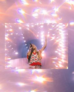 a woman standing on top of a stage with her arms in the air while holding a microphone