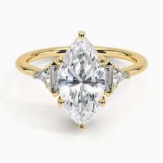 a yellow gold engagement ring with an oval cut diamond and three baguets on the side