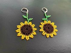 the beaded sunflower earrings are yellow and brown with green leaves on each side