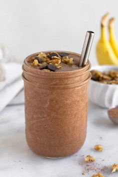 a glass jar filled with chocolate smoothie and granola