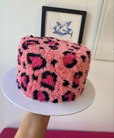 a pink and black cake sitting on top of a white plate next to a framed picture