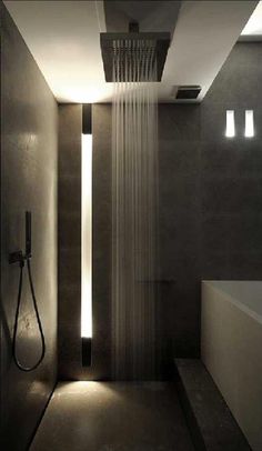 a shower head in the middle of a bathroom with lights on it's side