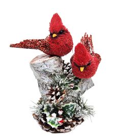 two red birds sitting on top of a pine cone