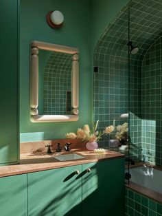 a bathroom with green tiles and wooden counter tops, along with a white sink under a large mirror