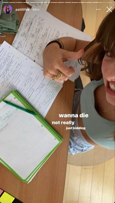 a woman sitting at a table with some papers on top of her and an open notebook in front of her