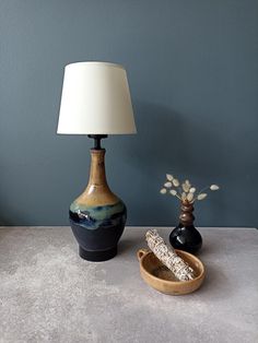 a table with two vases and a lamp on it next to a small bowl