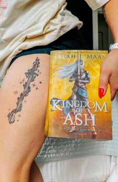 a woman with a tattoo on her thigh holding a book