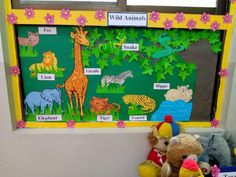 a stuffed animal sitting next to a bulletin board with animals on it's sides