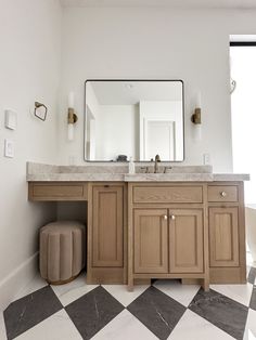 a bathroom with a checkered floor and large mirror on the wall above the sink