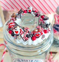 a glass jar filled with white frosting and candy canes on top of a table