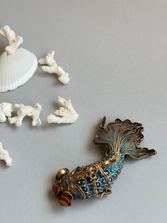 This exquisite antique koi fish pendant from the early 20th century is a true masterpiece of Chinese jewelry craftsmanship. Created using the intricate cloisonné technique, the pendant showcases delicate enamel work in vibrant shades of blue and red. Crafted in 925 sterling silver with a gold vermeil coating, the fish is composed of twelve articulated joints, lending it a lifelike, fluid motion. The piece bears the "Silver" mark, typical for Chinese-made antique charms. It weighs 28 g and measur Antique Charms, Carpe Koi, Chinese Jewelry, Fish Pendant, Silver Enamel, Koi Fish, Feng Shui, Gold Vermeil, Koi