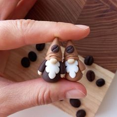 someone is holding two small figurines in their hand with coffee beans scattered around them