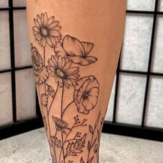 a close up of a person's leg with flowers on it and butterflies in the background