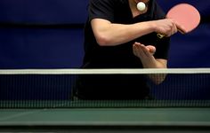 a man holding a tennis racquet in front of a ball on a ping pong court