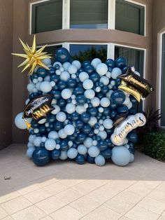 a balloon arch with balloons and confetti on it in front of a house