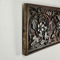 an intricately carved wood panel with flowers and leaves on the back side, mounted on a white wall