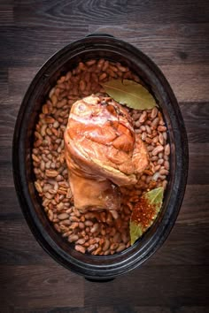 a bowl filled with beans and meat on top of a wooden table