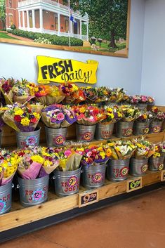 flowers are arranged in buckets on display for sale