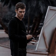 a man standing in front of an easel painting