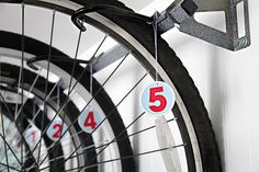 the number five is hanging on the front wheel of a bicycle, and it's spokes are numbered with red numbers