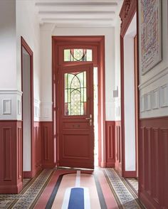 an entryway with red doors and striped carpet