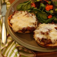 a plate with some food on it next to a fork and knife near a salad