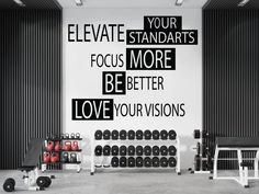 a gym room with black and white wall decals on the walls that say, elevate your standards focus more be better love your visions