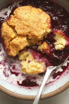 a close up of a bowl of food with berries and crumbs on it