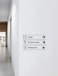 a white wall with some signs on it in an empty room that says toilet, shower room, restaurant