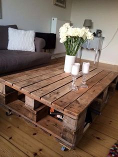 a coffee table made out of pallet wood with candles and flowers on it in a living room