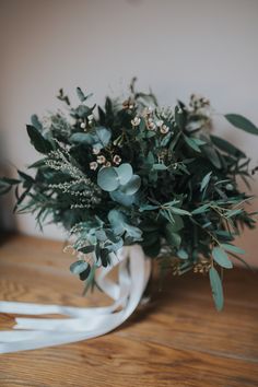 a bouquet of flowers sitting on top of a wooden table next to a white ribbon