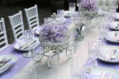 the table is set with white and purple plates, silverware, and an ornate carriage