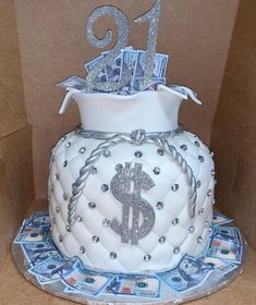 a white cake with silver decorations and money on top