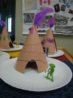 two paper plates that have some kind of tent on top of each other with purple feathers