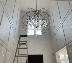 a chandelier hanging from the ceiling in a room with white walls and windows