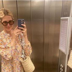 a woman taking a selfie with her cell phone in front of an elevator door