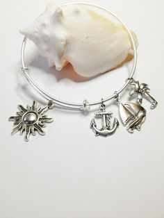 "Nautical Beach Sunburst adjustable stainless steel silver charm bangle Antique silver charms included: Sunburst Sailboat Palm tree Anchor Includes:  An expandable wire bangle which is made from solid stainless steel. It will not rust or tarnish and is hypoallergenic. ( Last photo triple loop) Additional Charms can be added on and will cost $1.50 per charm. To add a birthstone it will cost $2.50 more. To add a metal hand stamped initial or name disc will cost $4.00  Extra charms: 1...Jet ski 2.. Metal Charm Bracelets For Beach, Silver Charm Bracelet For The Beach, Adjustable Silver Charm Bracelet For Beach, Silver Charm Bracelet With Lobster Clasp For Beach, Handmade Charm Bangle For Beach, Life Ring, Womens Bangles, Metal Hand, Stainless Steel Bangles