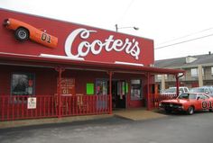 an orange car is parked in front of a red building with the word coote's on it