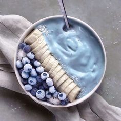 a bowl filled with blueberries, bananas and yogurt next to a spoon