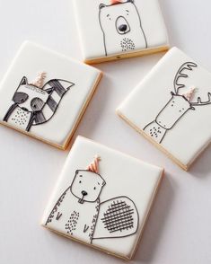 four decorated cookies with animals on them sitting on a white counter top next to each other