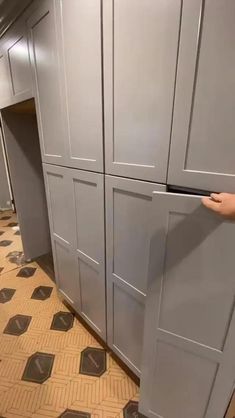 a person standing in front of some gray cabinets