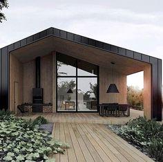 a small house with wooden floors and black accents on the roof is surrounded by greenery