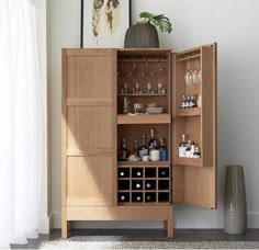 a cabinet with wine glasses and bottles in it next to a vase on the floor