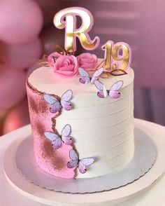 a white cake with pink and gold butterflies on it's top, sitting on a plate