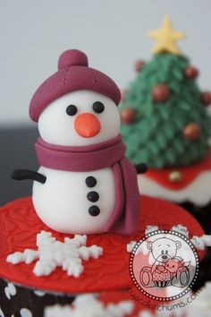 two cupcakes with frosting and decorations on them are decorated like snowmen