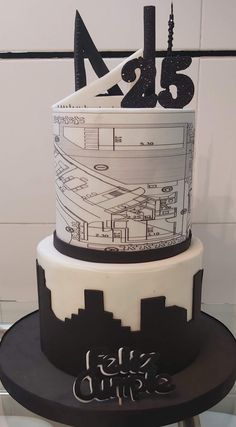 a three tiered cake with black and white icing on the top, decorated with an architectural design