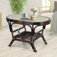 a wicker coffee table with two cups on it and a potted plant in the corner