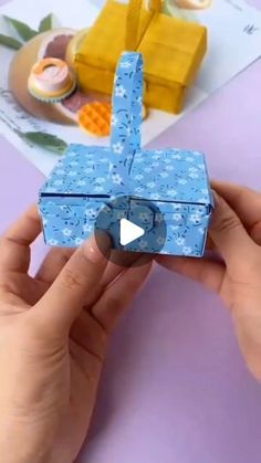 someone is holding an origami box that looks like a blue flowered box