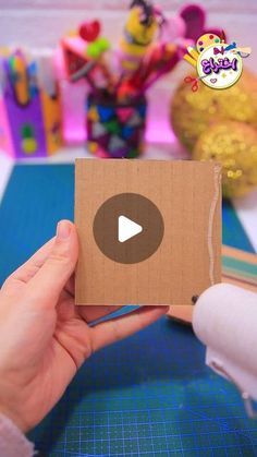 a person is holding a cardboard box with a video on it and there are other toys in the background